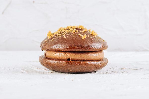 Chocolate Cherry Cheesecake Dairy Free & Vegan Whoopie Pie. Chocolate sponge with a Cheesecake filling and cherry compote centre. Side angle on a white background.